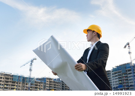 Young Chinese architect holding blueprints Young Chinese architect holding blueprints 14991923