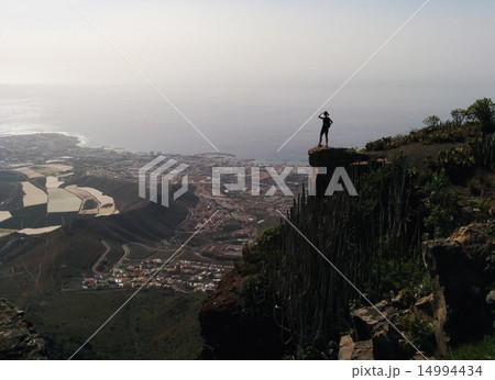 Woman on a edge of a mountain enjoying valley view Woman on a edge of a mountain enjoying valley view 14994434