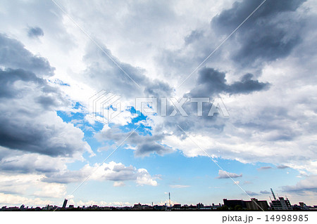 春の曇り空 雲の切れ間から覗く青空の写真素材