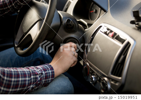 Closeup of man inserting key in car ignition lock 15019951