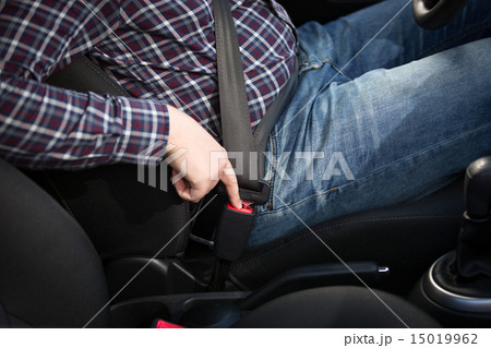 Young man driver pressing safety belt button in car 15019962
