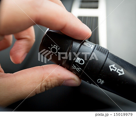 Closeup of man adjusting light control toggle in car 15019979