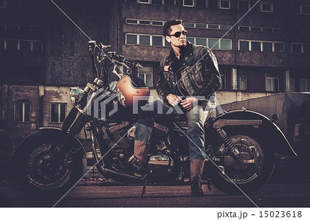 Biker and his bobber style motorcycle on a city streets 15023618