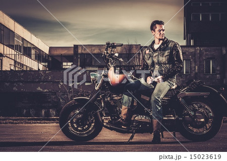 Biker and his bobber style motorcycle on a city streets 15023619