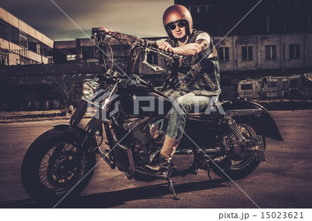 Tattooed biker and his bobber style motorcycle on a city streets 15023621