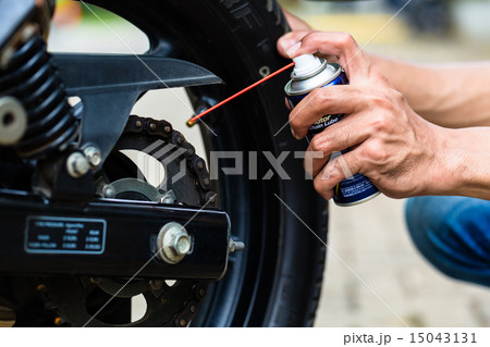 Man greasing motorcycle chain Man greasing motorcycle chain 15043131