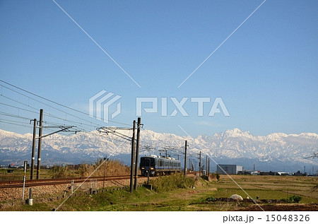 雪の北アルプス立山連峰を背景に走る「あいの風鉄道」 15048326