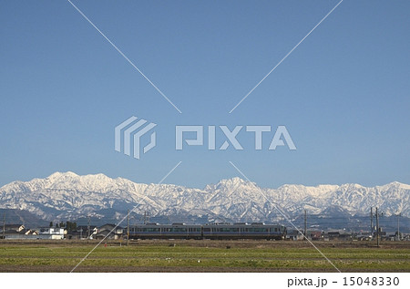 雪の北アルプス立山連峰を背景に走る「あいの風鉄道」 15048330