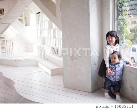 白い部屋で仲良く立っている赤ちゃんと女の子の写真素材