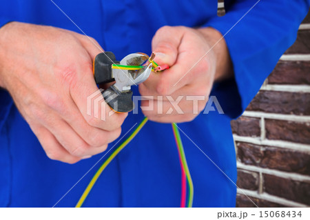 Composite image of electrician cutting wire with pliers 15068434