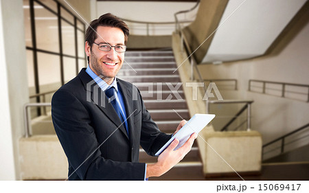 Composite image of businessman looking at the camera while using Composite image of businessman looking at the camera while using 15069417