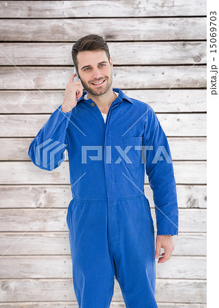 Composite image of smiling male mechanic using mobile phone 15069703