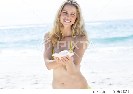 Smiling pretty blonde holding a seashell 15069821