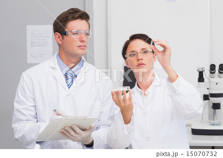 Scientists looking attentively at pill Scientists looking attentively at pill 15070732