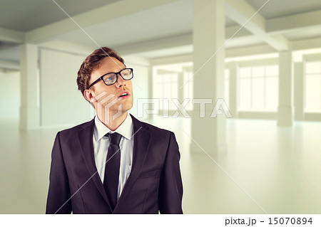 Composite image of young businessman thinking and looking up 15070894