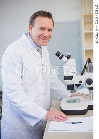 Smiling scientist examining sample with microscope Smiling scientist examining sample with microscope 15071822