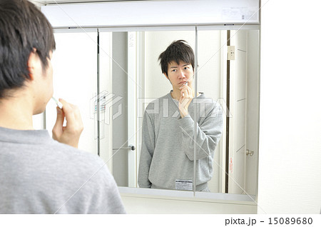 朝起きて洗面所の鏡の前で歯を磨く日本人男性 15089680