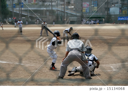 ネット裏から撮影した緊張感のある少年野球のワンシーンの写真素材