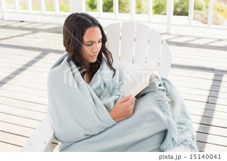Pretty brunette sitting on a chair and reading a book Pretty brunette sitting on a chair and reading a book 15140041