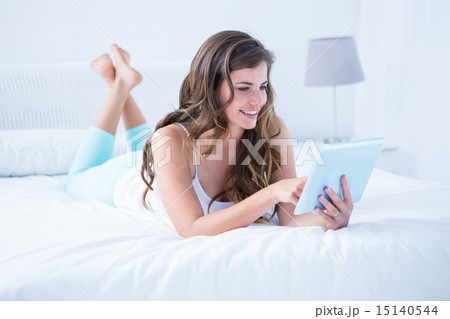Happy brunette using her laptop in her bed 15140544