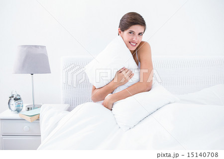 Happy brunette hugging her pillow 15140708