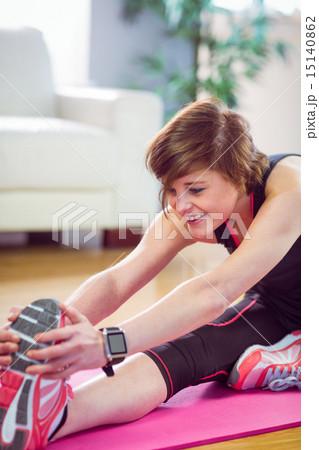 Fit woman stretching on exercise mat 15140862