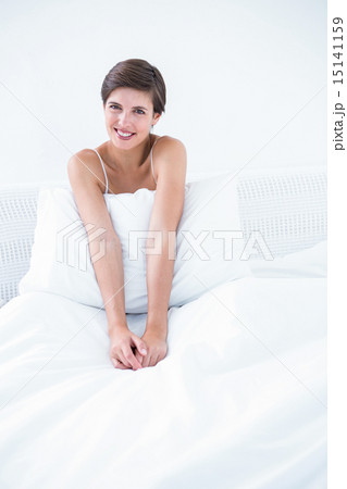 Happy brunette smiling at camera in her bed 15141159