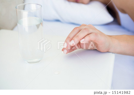 Pretty brunette taking pill on bed 15141982