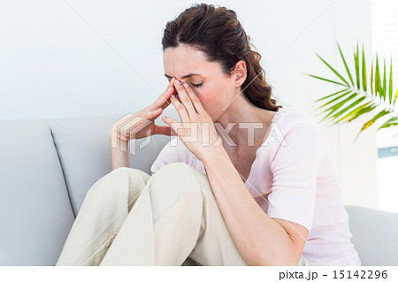 Sad brunette sitting on the couch 15142296