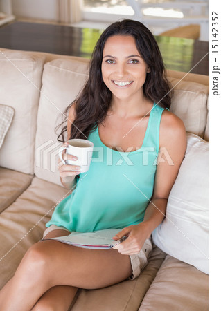 Pretty brunette reading magazine on the couch Pretty brunette reading magazine on the couch 15142352
