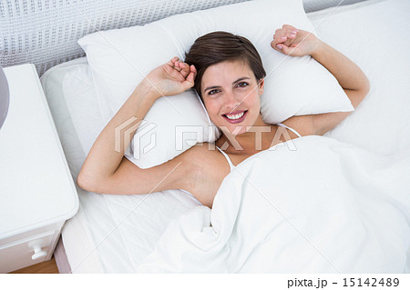 Relaxing woman in her bed smiling at camera 15142489