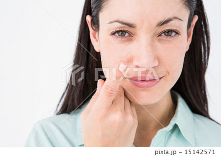 Brunette holding contact lens and smiling at camera 15142571