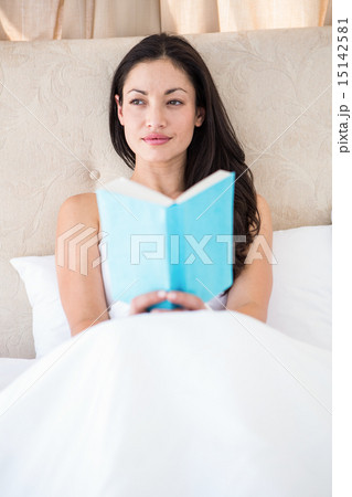 Pretty brunette reading on bed 15142581