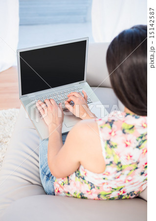 Pretty brunette using laptop on couch Pretty brunette using laptop on couch 15142587