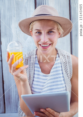 Pretty blonde woman using her tablet and holding orange juice 15143405