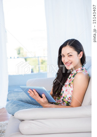 Pretty brunette looking at camera and using laptop on couch 15143407