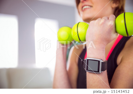 Fit woman lifting dumbbell sitting on ball 15143452