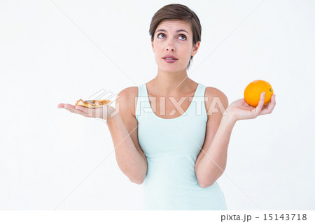 Woman choosing between pizza and an orange Woman choosing between pizza and an orange 15143718
