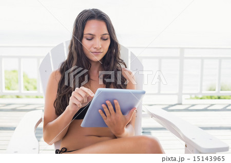 Pretty brunette sitting on a chair and using tablet pc Pretty brunette sitting on a chair and using tablet pc 15143965