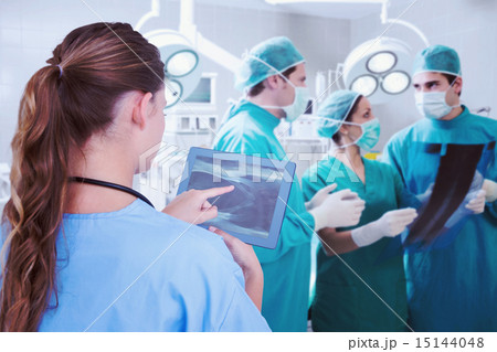 Composite image of doctor looking at xray on tablet 15144048