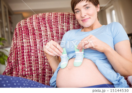 Pregnant woman holding baby shoes over bump 15144530