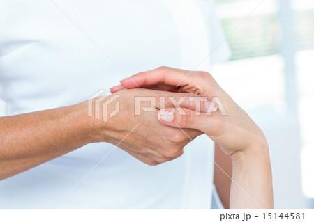 Physiotherapist examining her patients hand 15144581