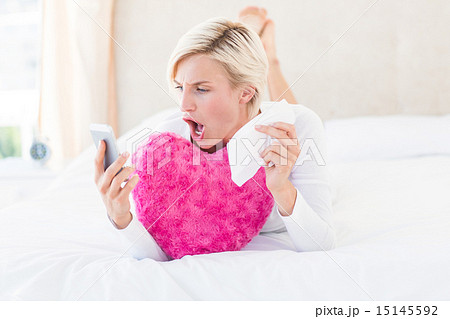 Shocked blonde woman lying on the bed and texting with her mobil Shocked blonde woman lying on the bed and texting with her mobil 15145592