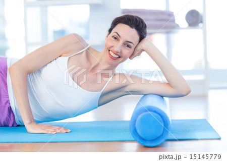 Smiling woman lying on exercise mat 15145779