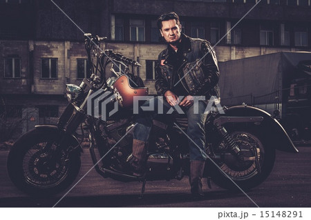 Biker and his bobber style motorcycle on a city streets 15148291
