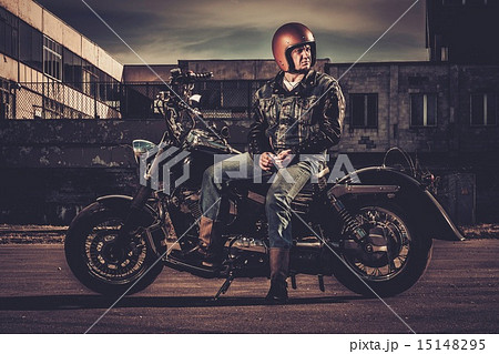 Biker and his bobber style motorcycle on a city streets 15148295
