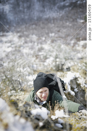 A man hiking in the mountains climbing up a steep rock face. 15160459