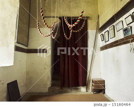 The bell ropes hanging from the roof and coiled for safety in the centre of the belfry of a church.  15160464