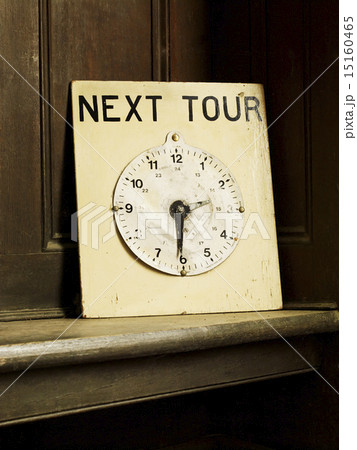 A clock face on a board with hands set to the time 2.30pm indicating the next guided tour of a house. 15160465