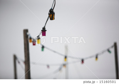 A multi-coloured string of electric lights against a grey sky. 15160501